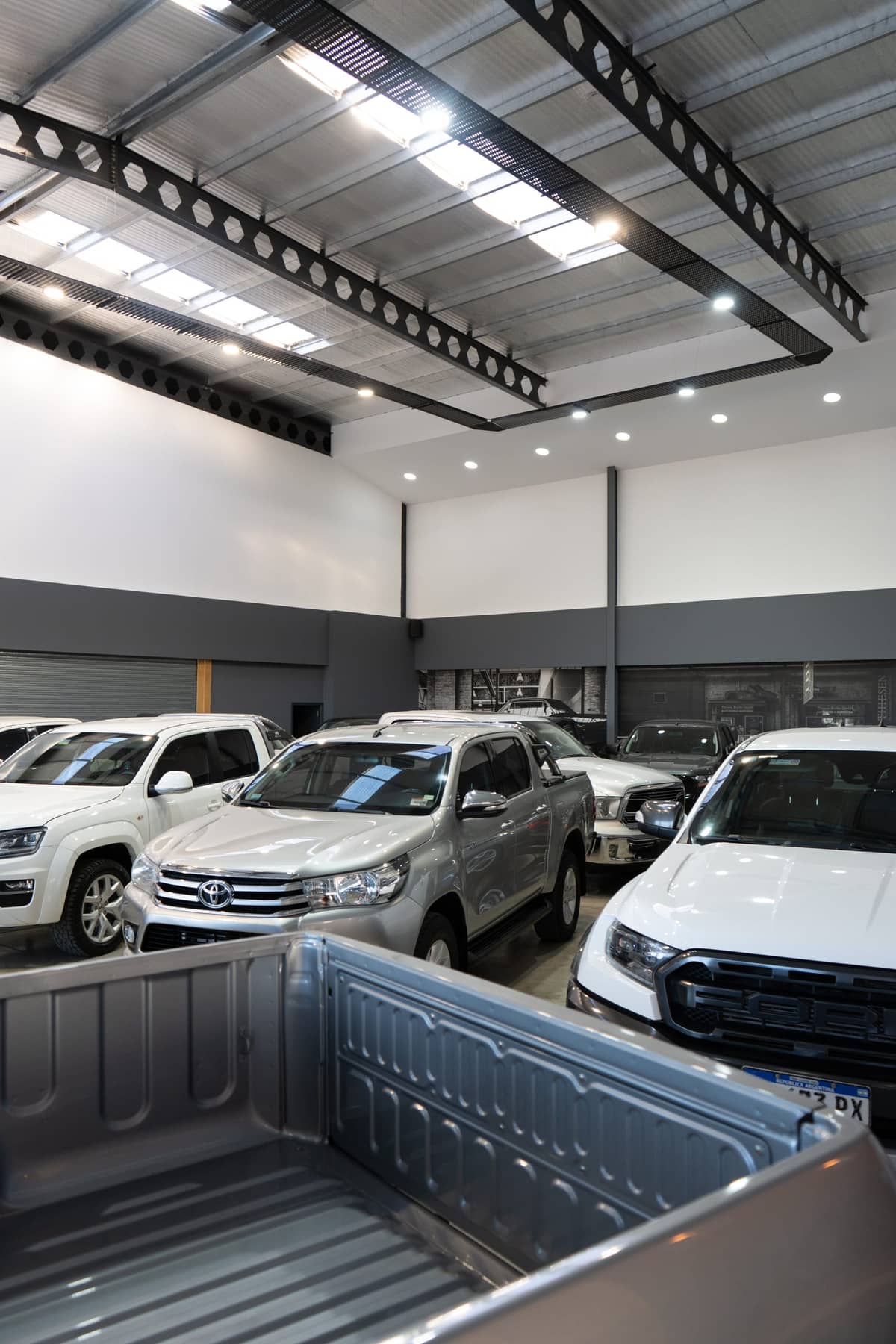 Salón de Berrini Automotores con pick-ups bajo el techo de vigas